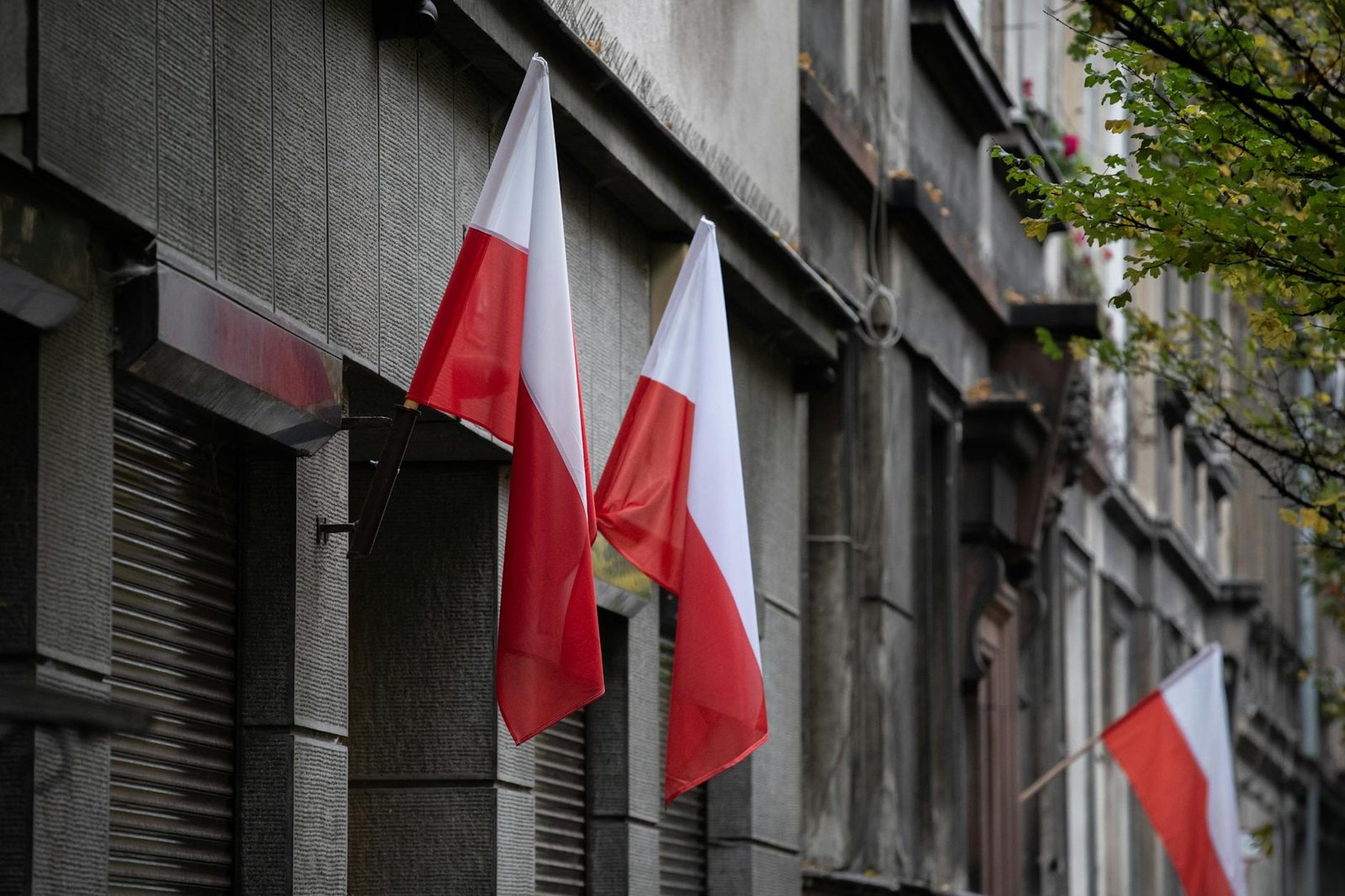 Polish flags on a historic building representing civic awareness and national heritage